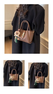 Close-up of brown litchi pattern leather bucket bag with lion plush pendant and gold hardware