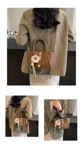 Detailed view of brown lychee texture leather bucket bag with lion plush charm and gold lock