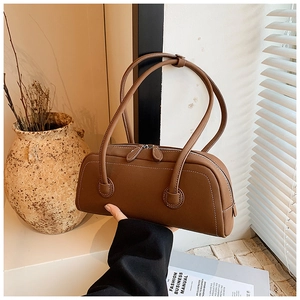 Detail of a brown leather tote bag with white contrast stitching and double zipper design