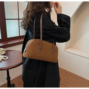 Detail of retro brown suede Boston bag showing soft texture and dark leather handles
