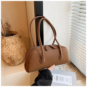Close-up of brown leather tote bag with white contrast stitching and dual zipper detail