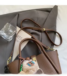 Detail of brown leather bucket bag with golden buckle and plush charm accessory