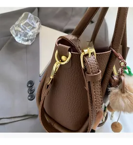 Close-up of brown litchi leather bucket bag with gold hardware and charm detail