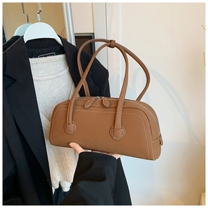 Detail of a brown matte leather tote bag with dual zippers and slim shoulder straps