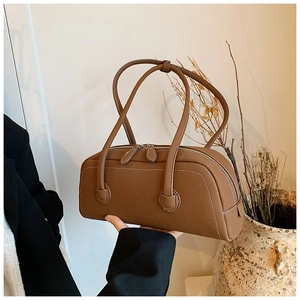 Detail of a brown leather tote bag with white stitching and long dual shoulder straps