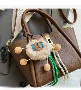 Detail of brown litchi grain leather bucket bag with gold lock and lion plush charm