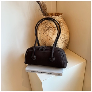 Detailed view of deep brown cylindrical tote with white contrast stitching and long straps
