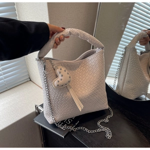 Détail de la texture tressée du sac seau en similicuir avec breloque cœur et chaîne