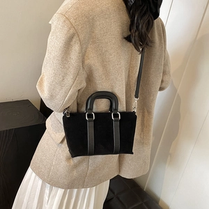Matte black vintage satchel bag with leather handles shown in a lifestyle indoor setting