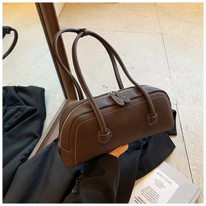 Detail of dark brown tote bag with white contrast stitching and dual zipper hardware