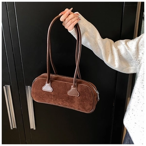 Detailed view of coffee brown suede bowling bag held by hand with silver zip closure