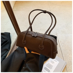 Detail of dark brown barrel tote bag with white contrast stitching and double zippers