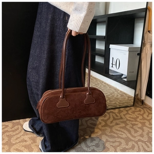 Detail of retro brown suede bowling bag with long leather handles and metal zipper