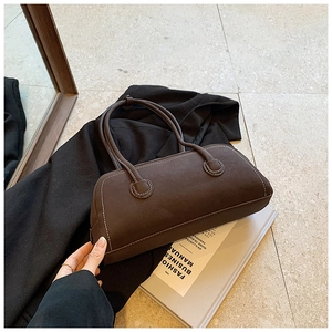 Detail of dark brown tote bag with contrast stitching and elongated retro handles