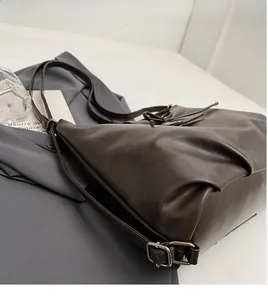 Detail of dark brown leather bucket bag featuring soft pleated sides and bow drawstring