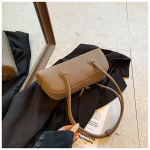 Detail view of taupe leather tote bag with white contrast stitching on black blazer
