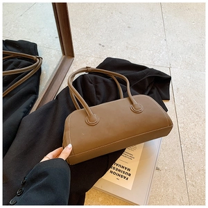 Detailed shot of brown tote bag with white contrast stitching on a black blazer