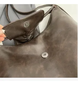 Detail of dark brown vintage faux leather hobo bag with a silver magnetic snap closure