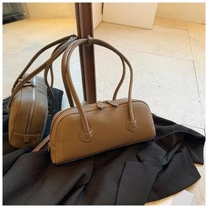 Detail view of dark camel tote bag with white stitching and long slim shoulder straps