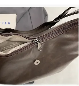 Detail of smooth metal zipper and herringbone fabric lining on brown shoulder bag