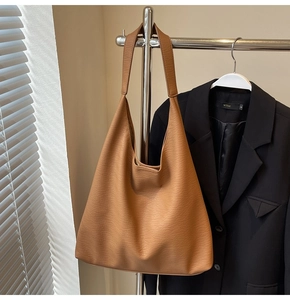 Detail of tan brown large tote bag with lychee texture hanging on a metal rack