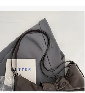 Detail view of dark brown faux leather bag with bow accent and soft pleated texture