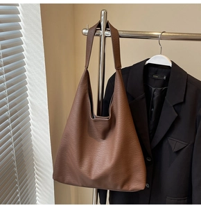 Close-up of a brown lychee pattern leather Hobo bag hanging in a minimalist studio