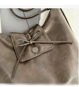 Detail of dark brown vintage PU leather bag featuring a bow tie and metal button accent
