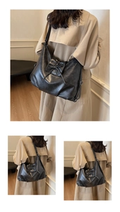 Detail of matte black leather tote bag featuring a decorative bow and metal buckle accent