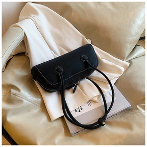 Close-up of black tote bag with white contrast stitching on a beige leather sofa