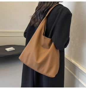 Model wearing a brown pebbled leather tote bag showing large capacity and drape