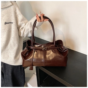Dettaglio borsa tote retrò marrone scuro con manici lunghi e fibbia in metallo oro