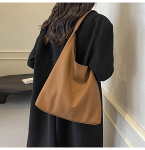 Close-up of caramel brown tote bag with litchi grain texture on model's shoulder
