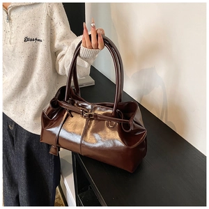 Dettaglio borsa tote in pelle marrone scuro lucida con fibbia in metallo e finitura fine