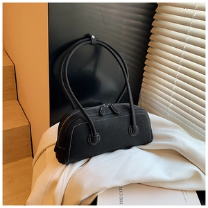 Detail of black leather tote bag with white contrast stitching and dual metal zippers
