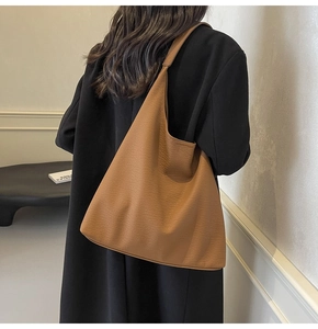 Brown leather hobo bag for women worn by model in a modern interior setting