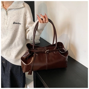 Dettaglio di una borsa tote in pelle lucida testa di moro con fibbia metallica e manici lunghi
