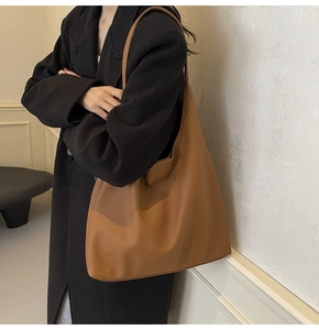 Close-up of caramel tote bag with lychee leather texture worn over black coat
