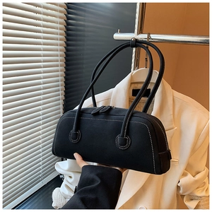 Detail of black suede tote bag featuring white contrast stitching and dual cylindrical handles