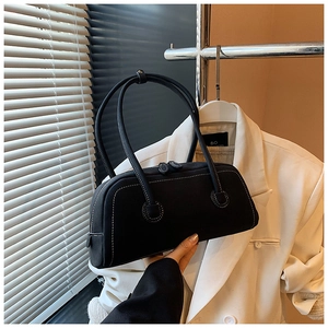 Detail view of black canvas tote bag with white contrast stitching and dual zippers