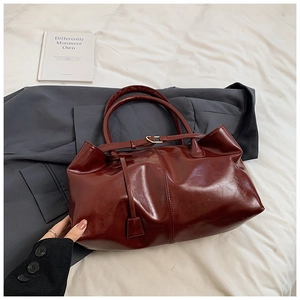 Dettaglio macro della pelle lucida rosso scuro e delle cuciture fini su una borsa tote