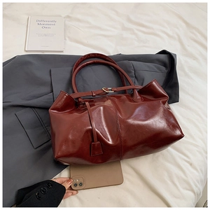 Dettaglio della borsa tote in pelle bordeaux lucida su sfondo lifestyle con texture