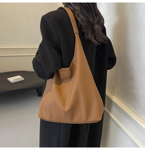 Detail of a large brown leather tote bag with lychee grain, shown over the shoulder