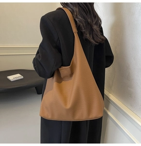 Brown leather tote bag detail on a model with minimalist modern office background