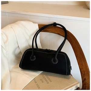 Detail of minimalist black tote bag with white contrast stitching on a wooden chair