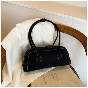 Detail of a black tote bag with white contrast stitching on a wooden chair background