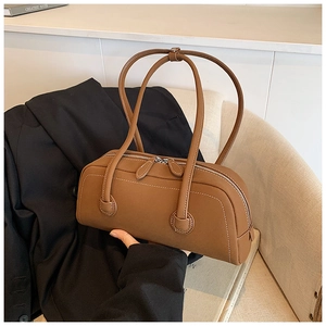 Detail of a brown leather barrel bag with white contrast stitching and double zippers