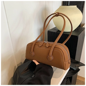 Detail of brown leather tote bag with contrast stitching and dual zipper closure