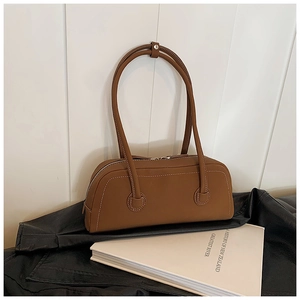 Detail of a brown leather underarm bag with white contrast stitching and long straps
