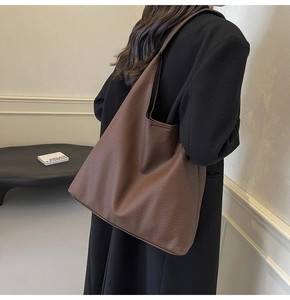Close-up of large dark brown tote bag with litchi grain texture and minimalist design